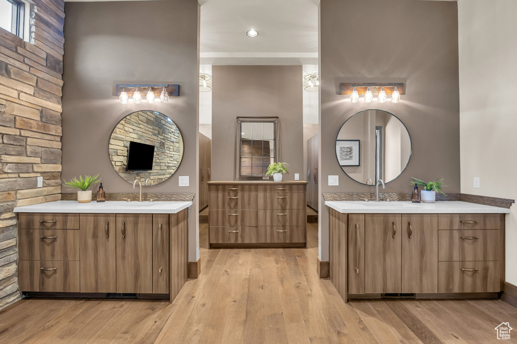 Full bathroom with two vanities, wood finished floors, and baseboards