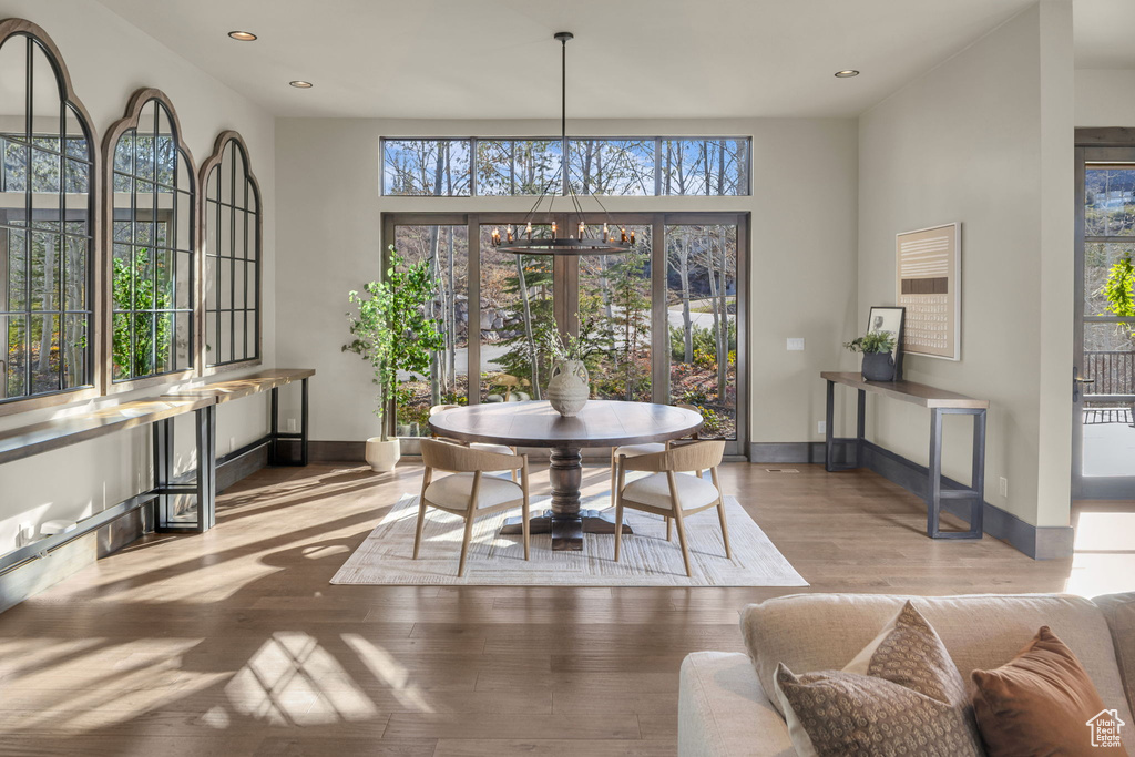 Dining space featuring healthy amount of natural light, wood finished floors, a chandelier, baseboards, and recessed lighting