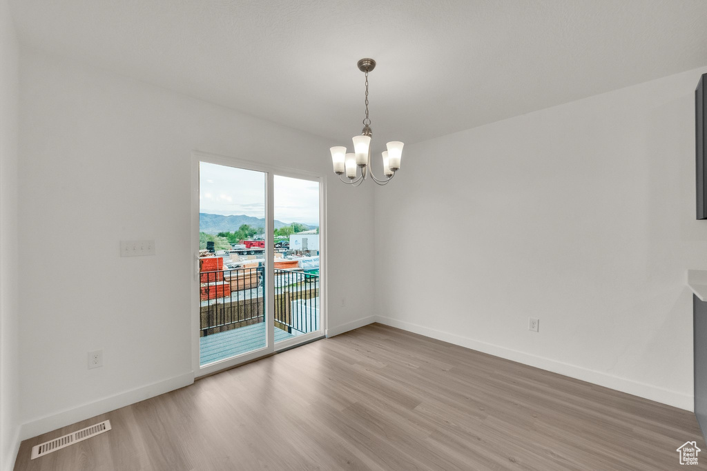 Unfurnished room with light wood-type flooring, a chandelier, and baseboards