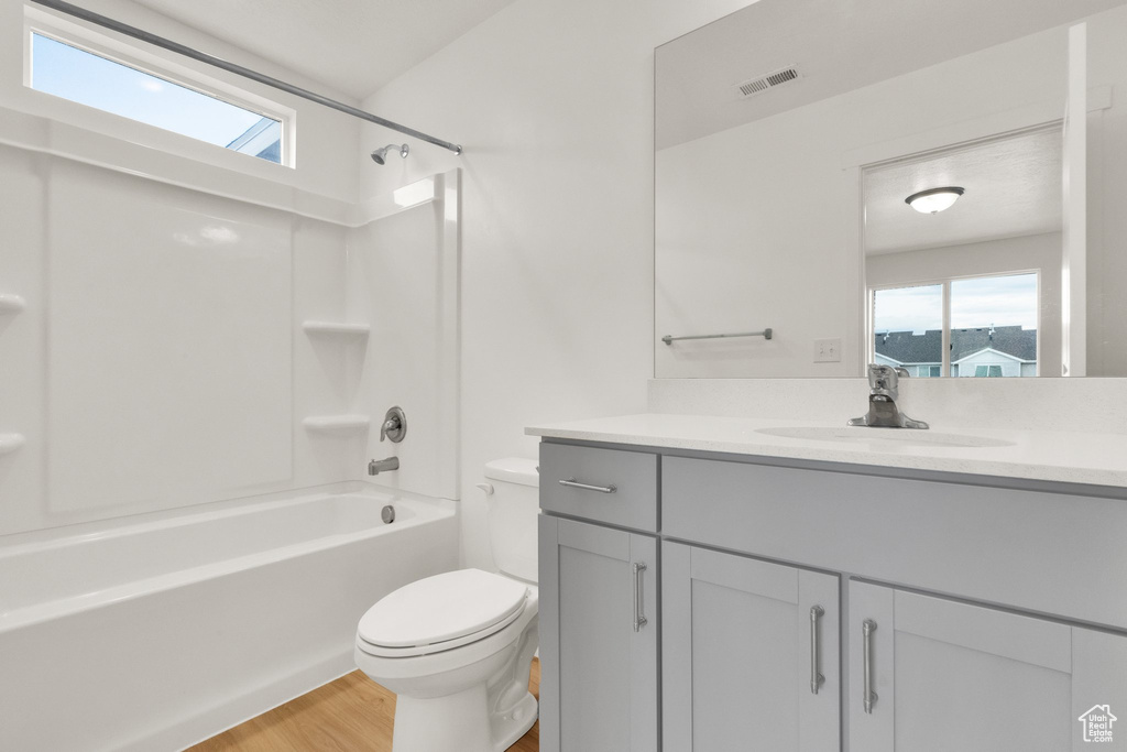 Bathroom featuring toilet, wood finished floors, vanity, and shower / bath combination