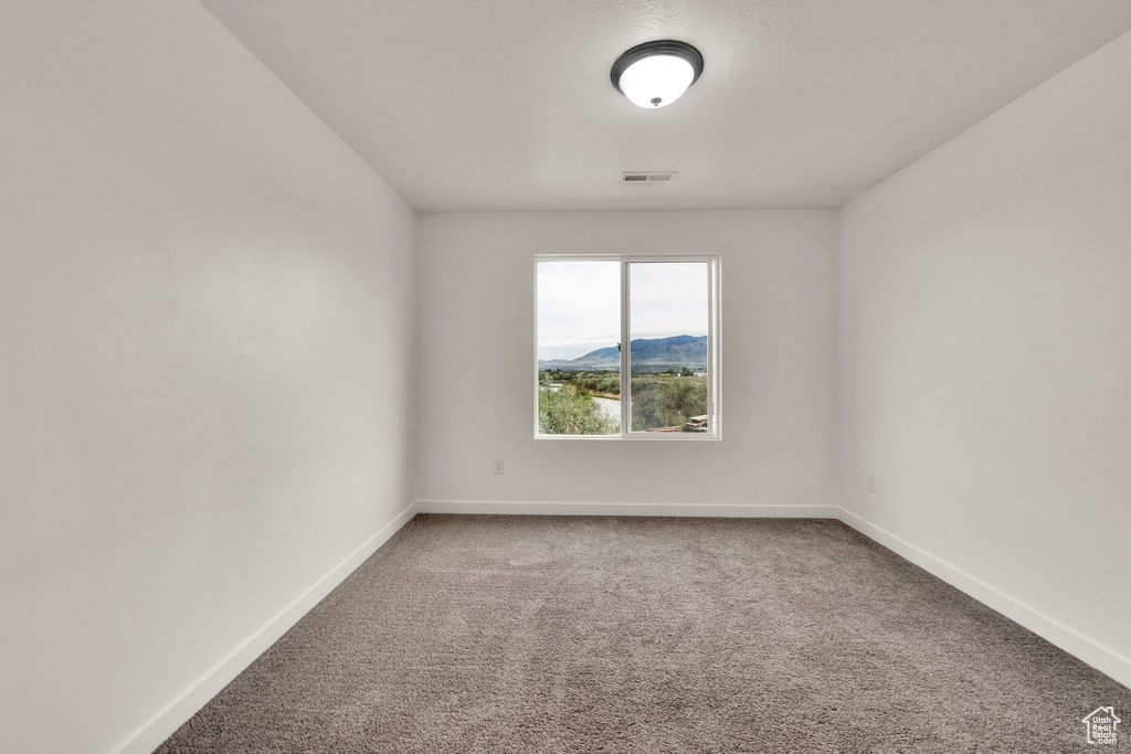 Carpeted spare room with baseboards and a mountain view