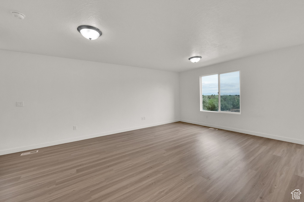 Empty room with wood finished floors, baseboards, and a smoke detector