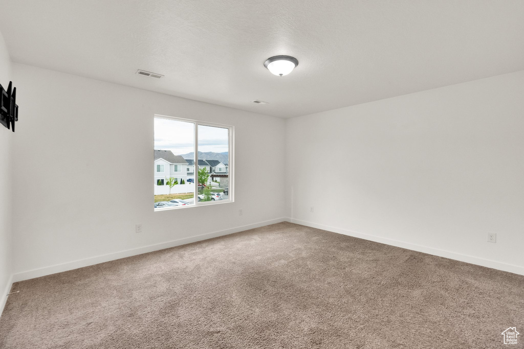 Carpeted spare room featuring baseboards