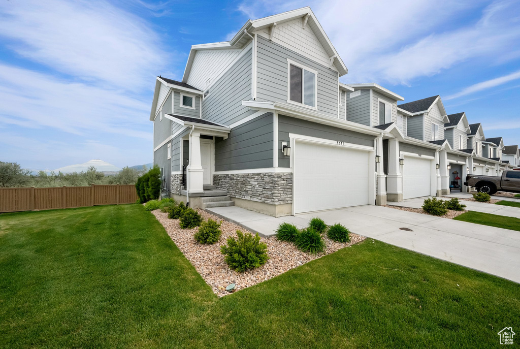 View of front of house featuring stone siding, driveway, and an attached garage