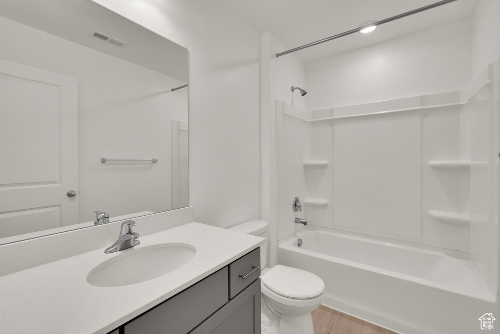 Full bathroom featuring toilet, wood finished floors, vanity, and tub / shower combination