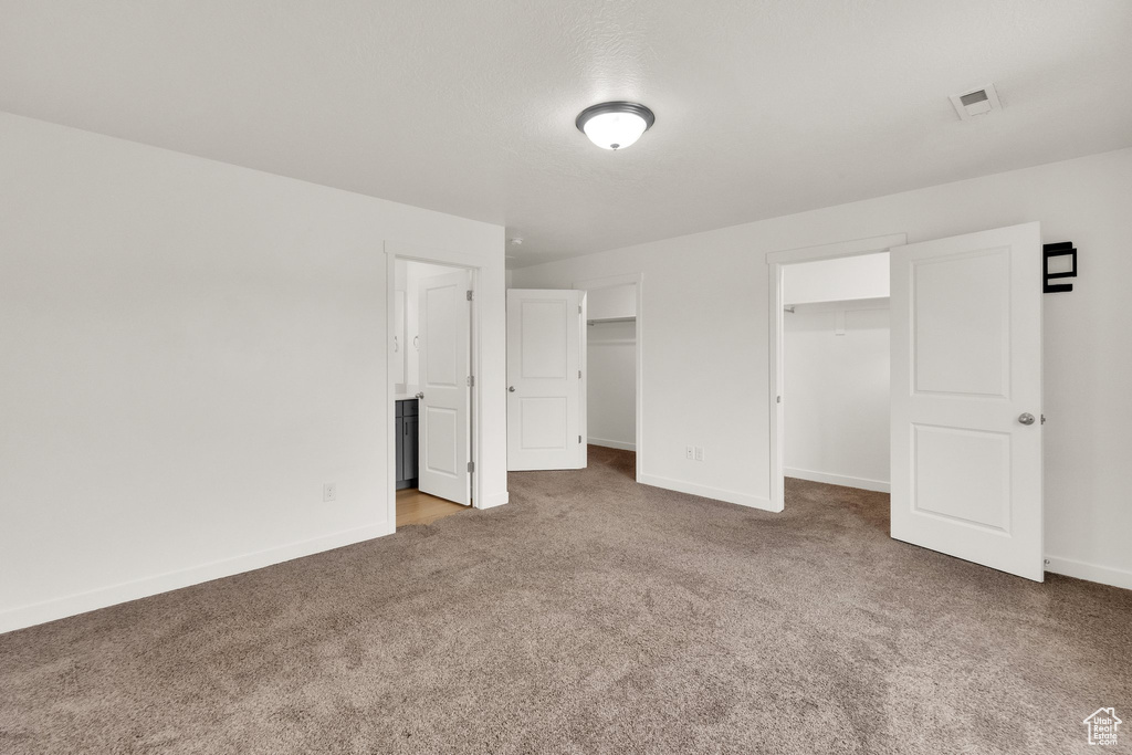 Unfurnished bedroom featuring carpet flooring, baseboards, and a spacious closet