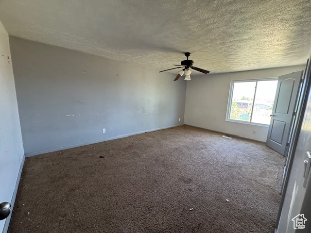 Carpeted empty room with a textured ceiling, ceiling fan, and baseboards