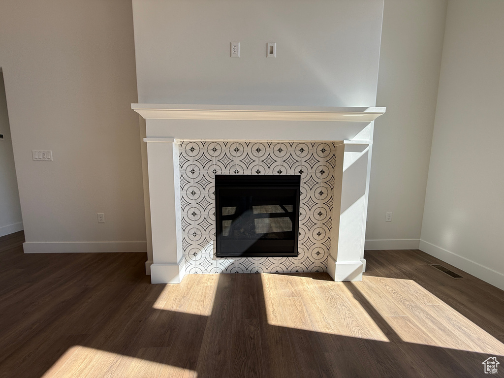Detailed view of a tiled fireplace, baseboards, and wood finished floors