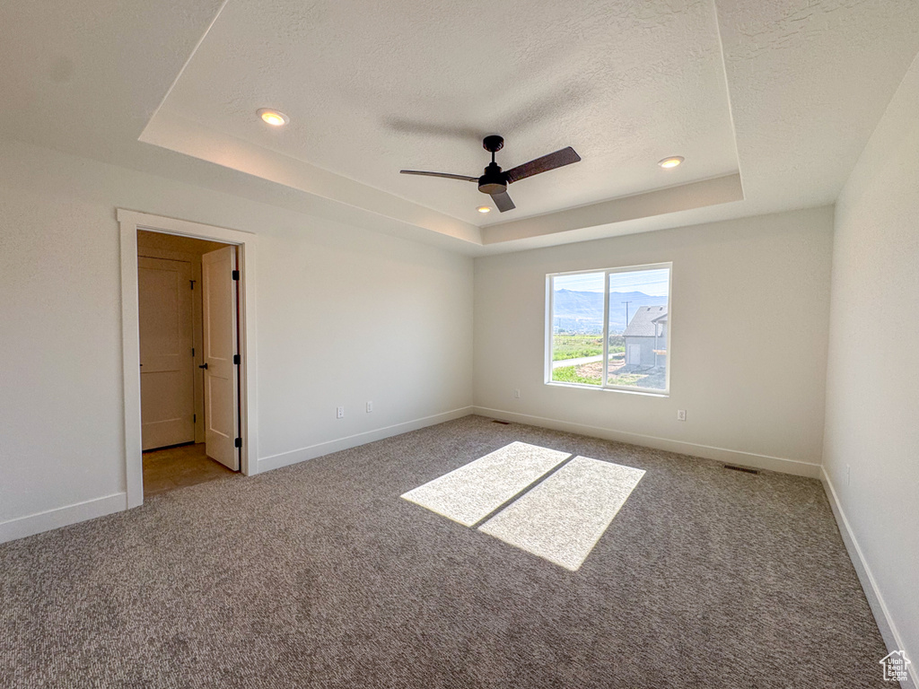 Carpeted empty room with a tray ceiling, a textured ceiling, a ceiling fan, and recessed lighting