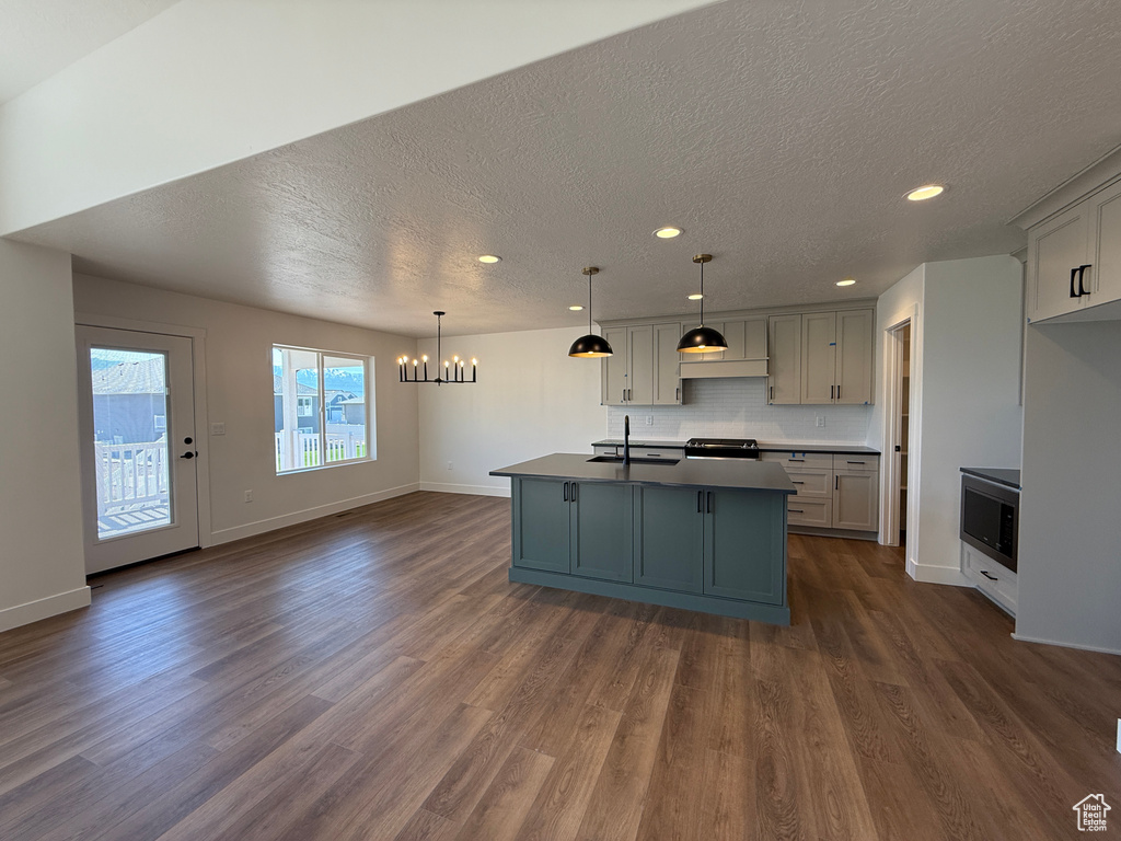 Kitchen featuring a textured ceiling, a chandelier, recessed lighting, dark wood finished floors, and a sink