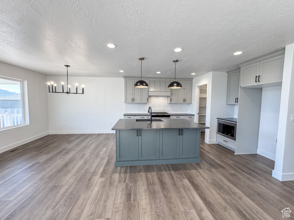 Kitchen with stainless steel microwave, gray cabinetry, a textured ceiling, a chandelier, and dark countertops
