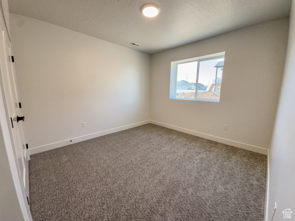 Spare room with a textured ceiling and carpet