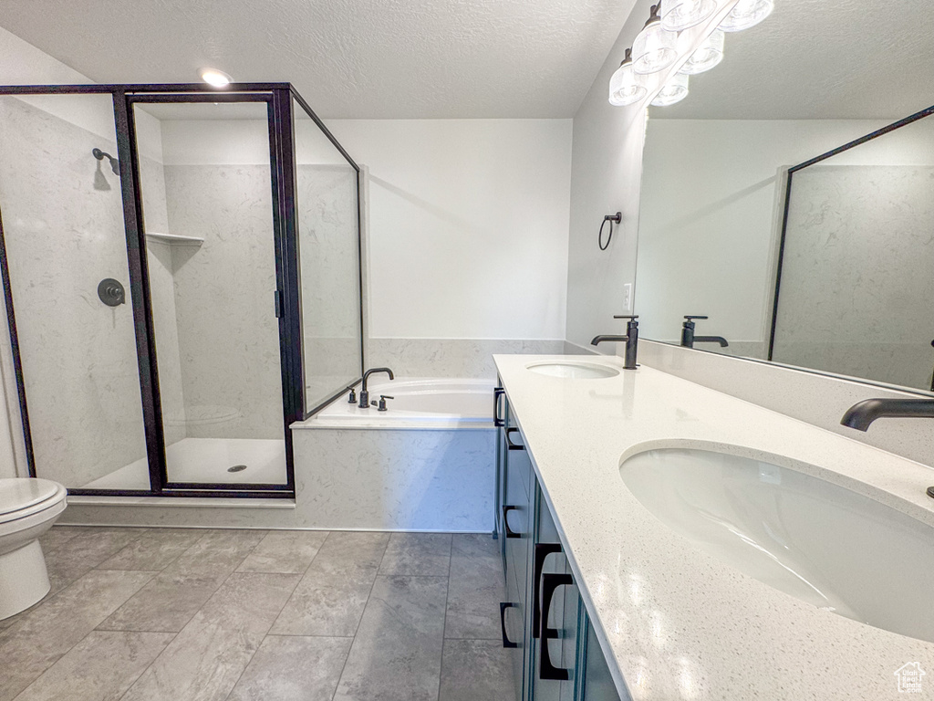 Full bath featuring a garden tub, a stall shower, double vanity, and a textured ceiling