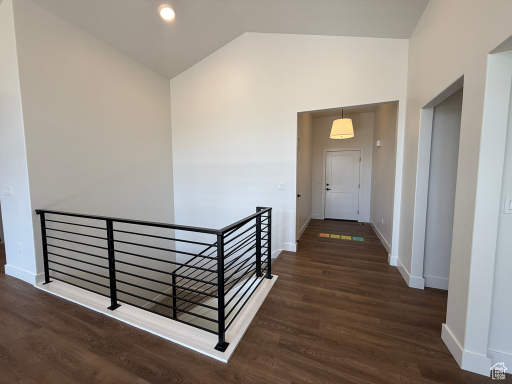 Hall with an upstairs landing, lofted ceiling, wood finished floors, and baseboards