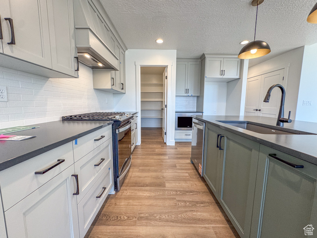 Kitchen featuring stainless steel appliances, dark countertops, light wood-style flooring, a textured ceiling, and recessed lighting