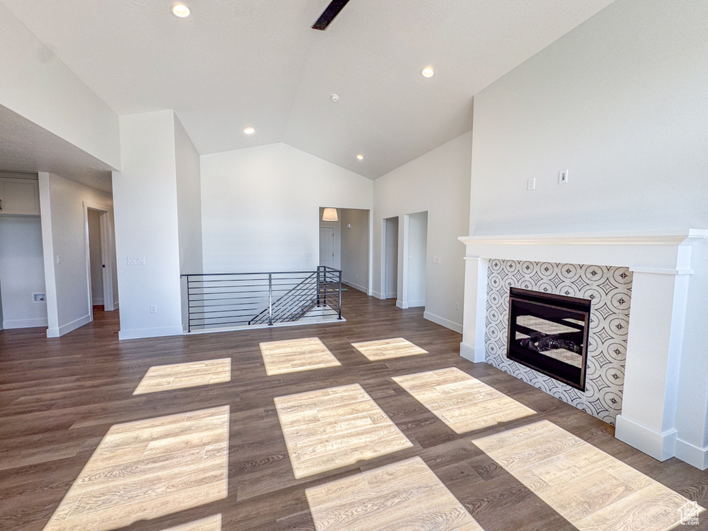 Unfurnished living room with vaulted ceiling, wood finished floors, recessed lighting, and a tile fireplace
