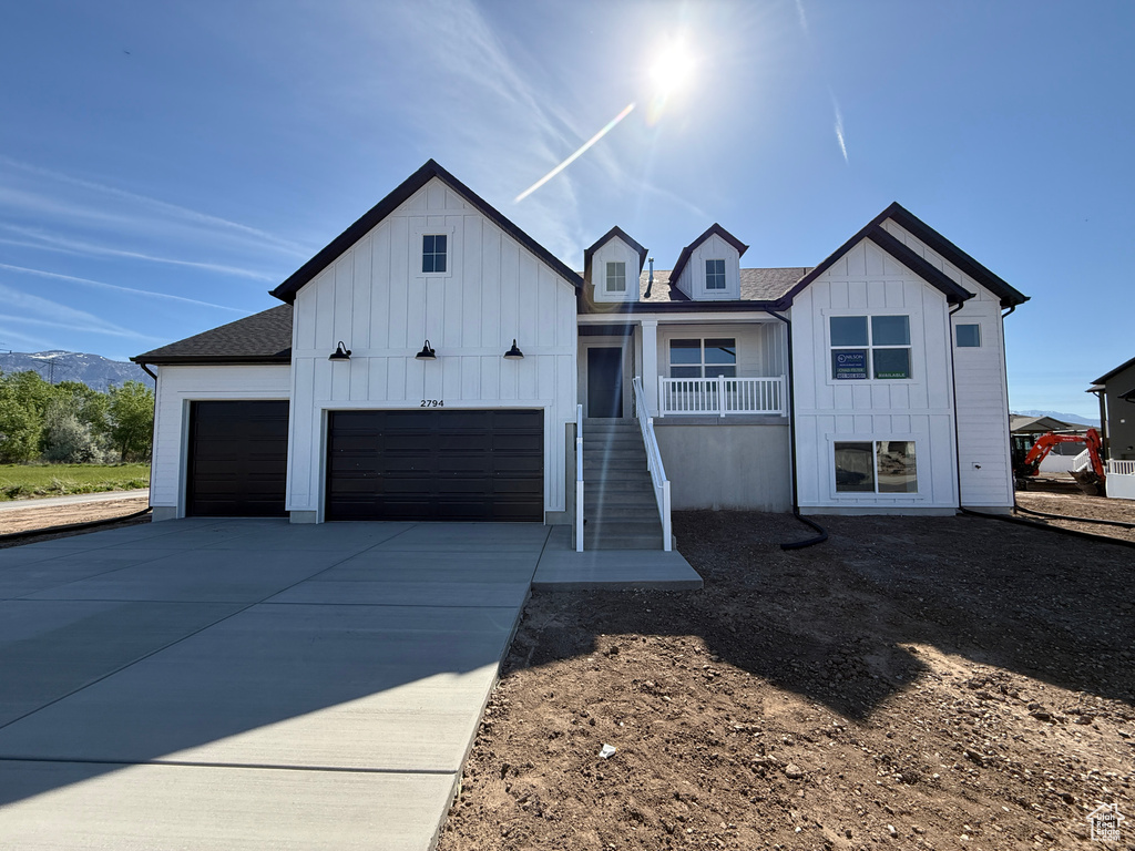 Modern farmhouse featuring board and batten siding, stairway, an attached garage, and concrete driveway