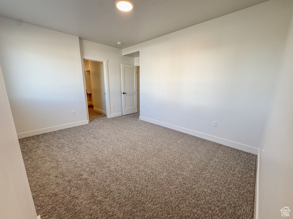 Carpeted spare room featuring baseboards