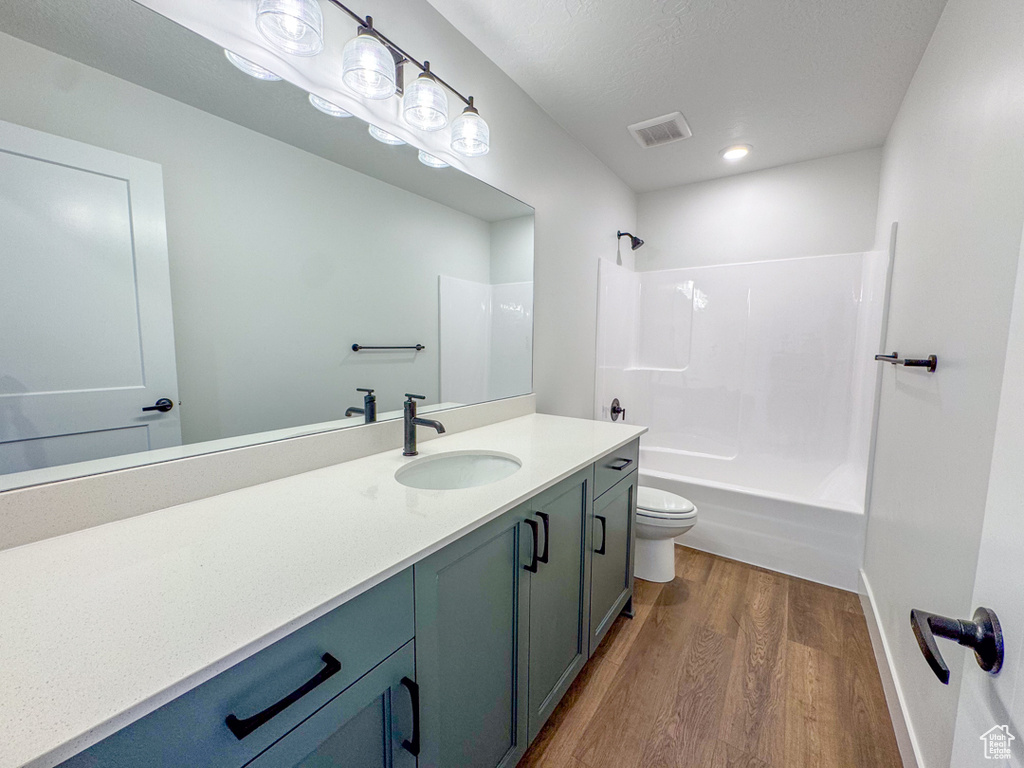 Bathroom featuring wood finished floors, vanity, tub / shower combination, and recessed lighting