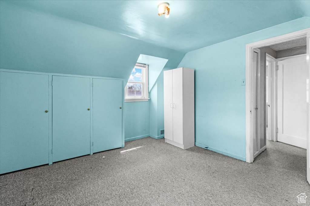 Additional living space with carpet flooring and vaulted ceiling