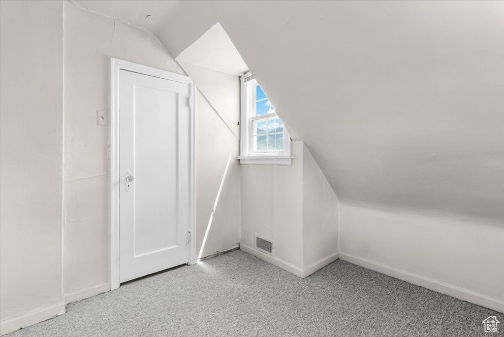 Bonus room with lofted ceiling, light carpet, and baseboards