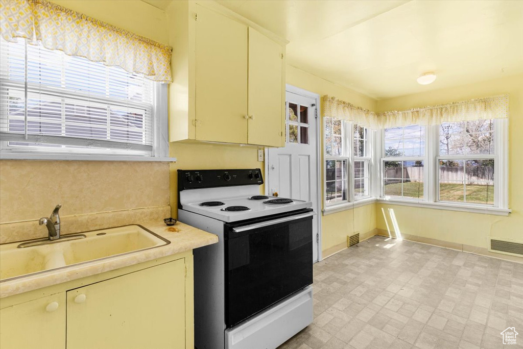 Kitchen with electric range, a sink, light countertops, and healthy amount of natural light