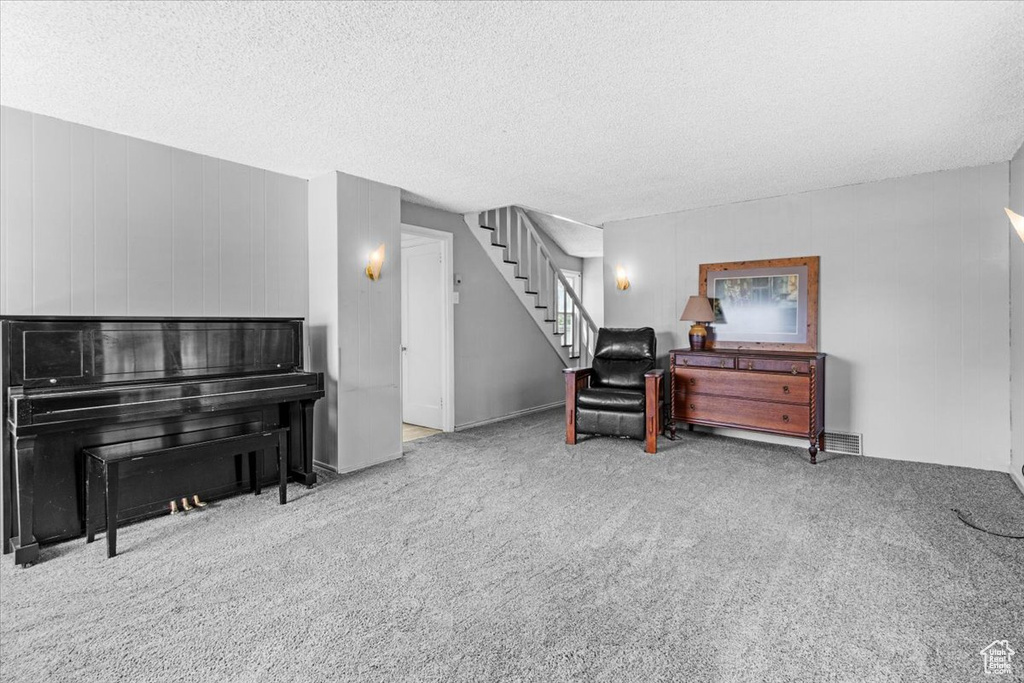 Living area featuring carpet flooring, stairway, and a textured ceiling