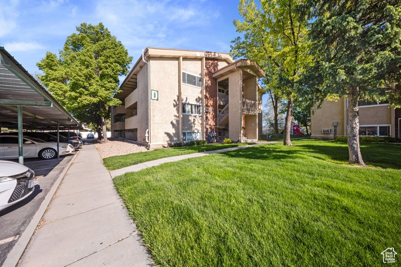 View of front of property with a front lawn, stucco siding, and covered parking