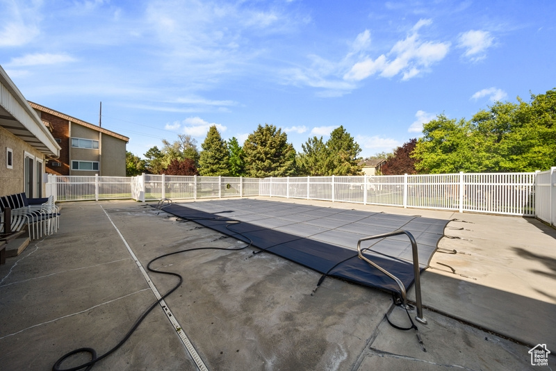 View of swimming pool with a patio and fence