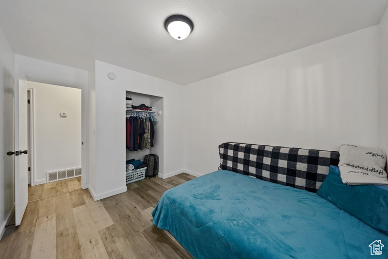 Bedroom featuring light wood-style floors, baseboards, and a closet