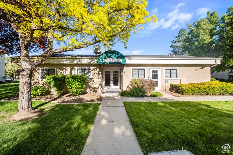 View of front of home with french doors, a front lawn, and stucco siding
