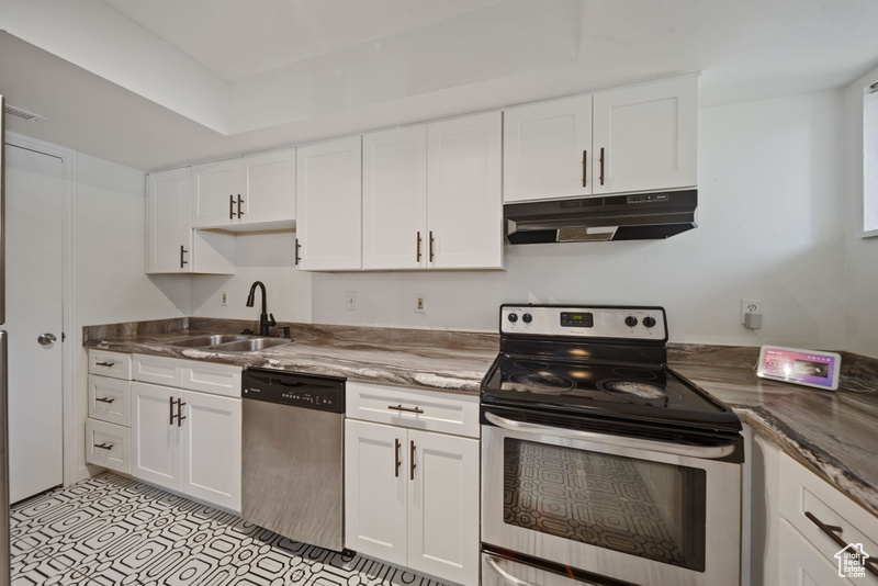 Kitchen featuring stainless steel appliances, a sink, under cabinet range hood, and white cabinets