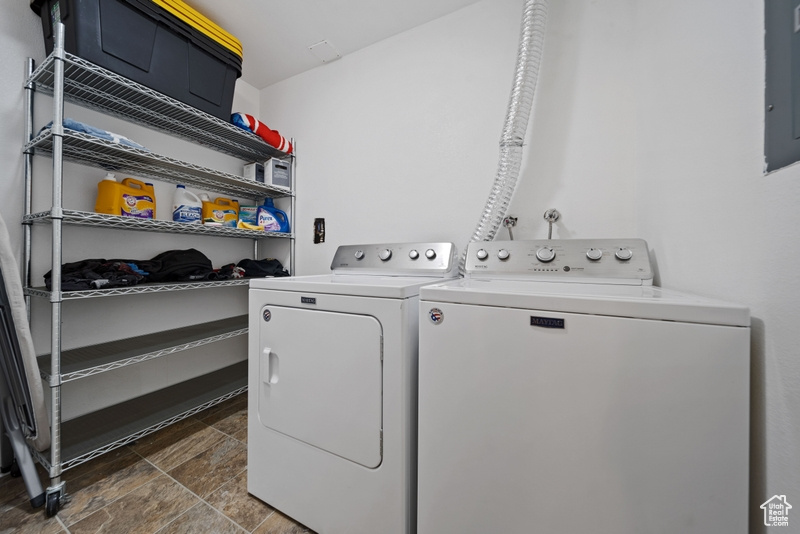Clothes washing area with washing machine and dryer and stone finish flooring