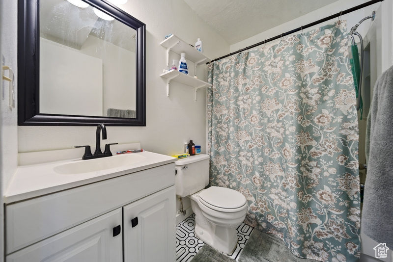 Full bath featuring toilet, vanity, tile patterned floors, and a shower with curtain
