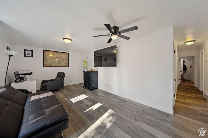 Living area featuring ceiling fan, wood finished floors, and baseboards