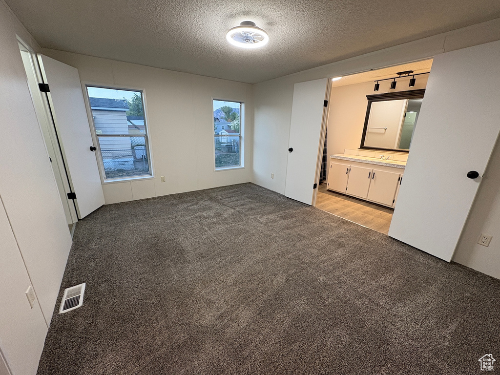 Unfurnished bedroom with light colored carpet, a textured ceiling, and ensuite bath