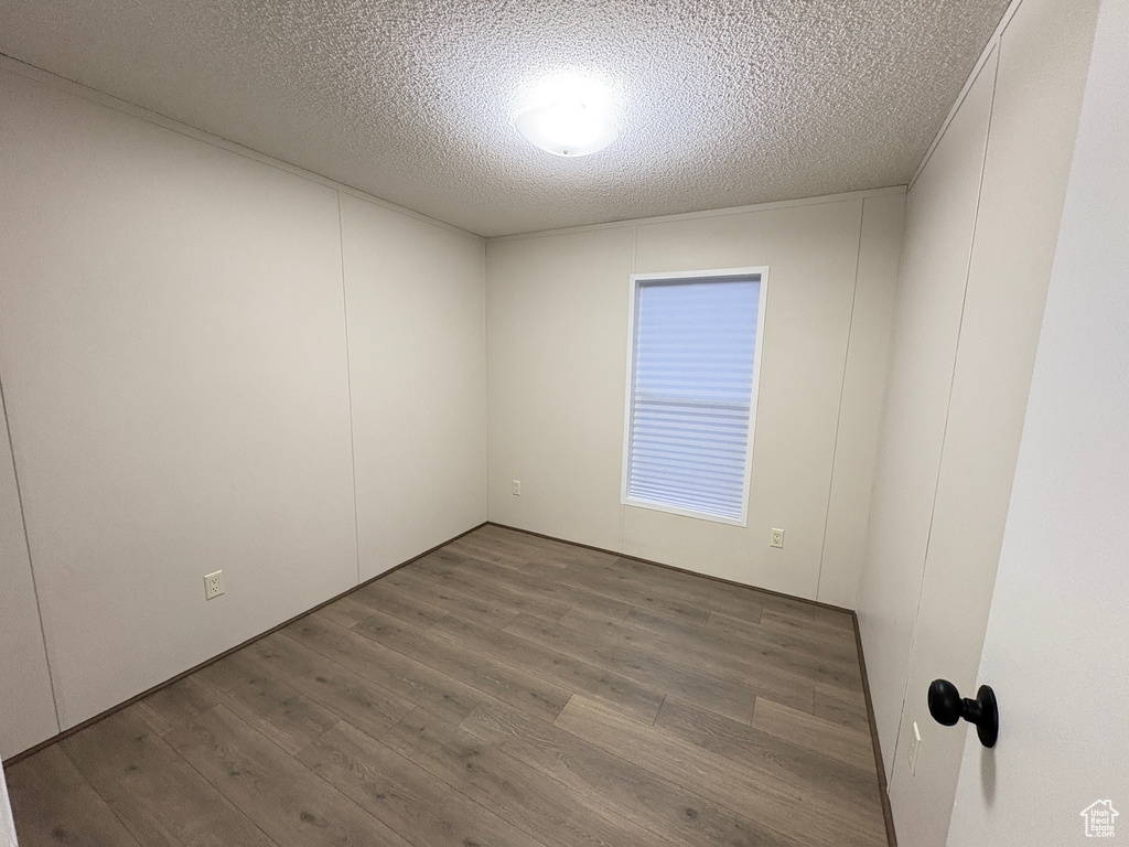 Empty room featuring wood finished floors and a textured ceiling