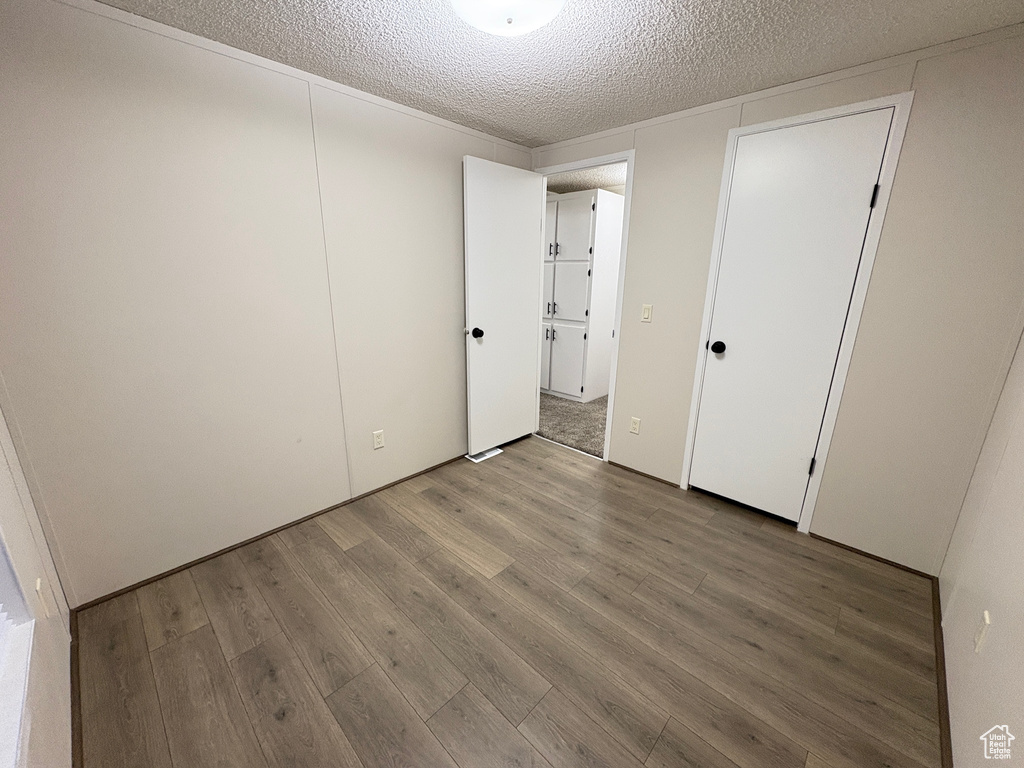 Unfurnished bedroom with wood finished floors and a textured ceiling