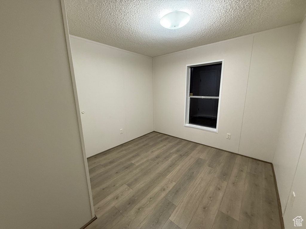 Empty room with a textured ceiling and wood finished floors