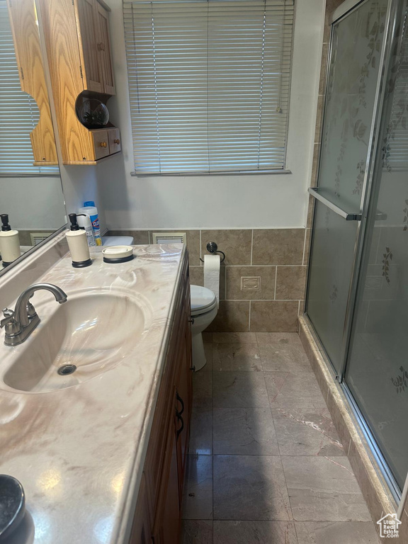 Full bath featuring a stall shower, toilet, vanity, and tile walls