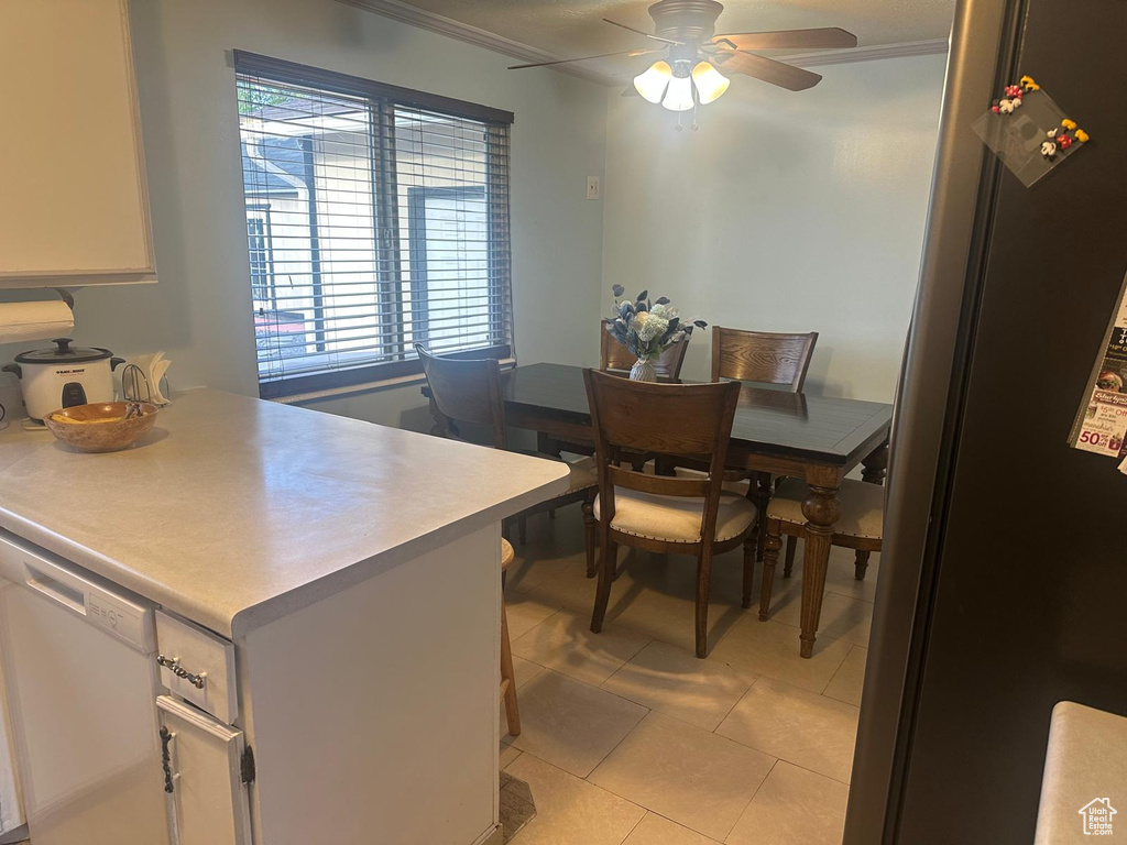 Dining area with ceiling fan, light tile patterned flooring, and crown molding