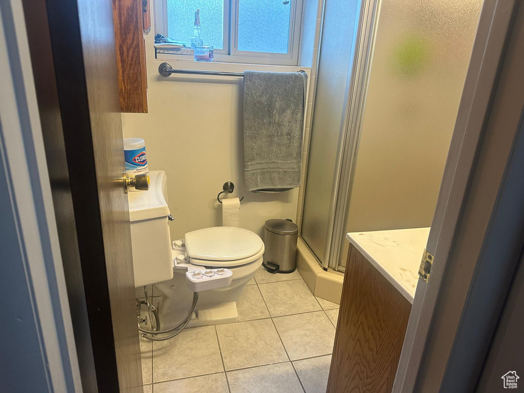Full bath with tile patterned flooring, a shower with door, vanity, and toilet