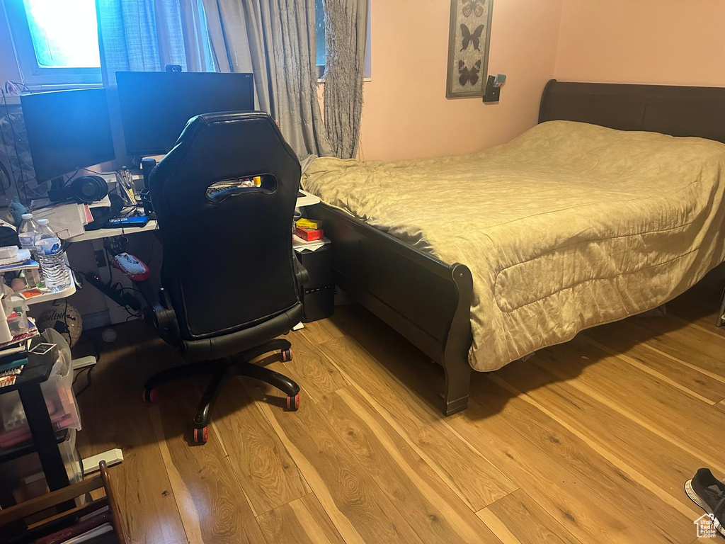 Bedroom with wood finished floors and an office area