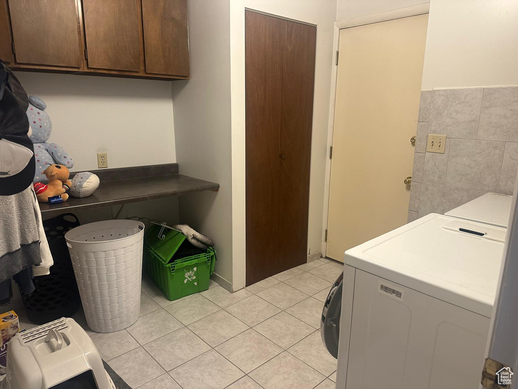Laundry area featuring cabinet space, light tile patterned flooring, and washing machine and clothes dryer