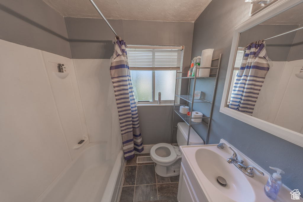 Full bath featuring toilet, shower / tub combo, tile patterned floors, vanity, and a textured ceiling