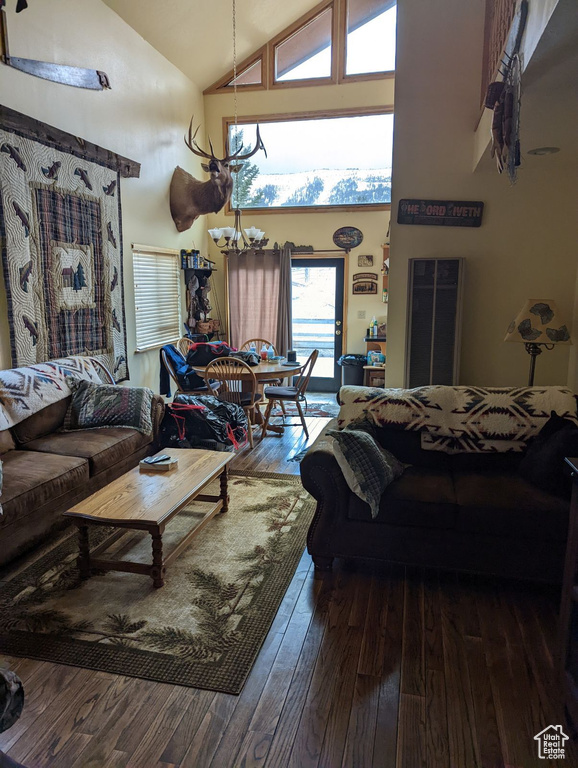 Living room with a chandelier, hardwood / wood-style flooring, and high vaulted ceiling
