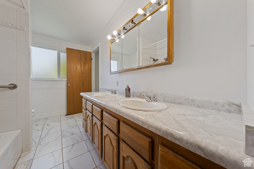 Full bath with marble finish floors, double vanity, ornamental molding, a bath, and toilet