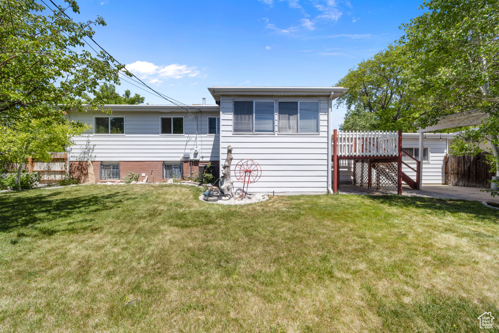 Rear view of house featuring a deck and a yard