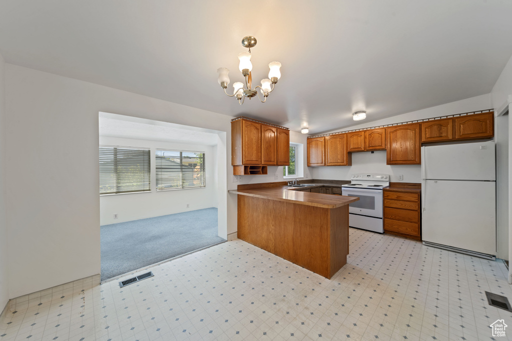 Kitchen with white appliances, a sink, brown cabinets, a peninsula, and a chandelier