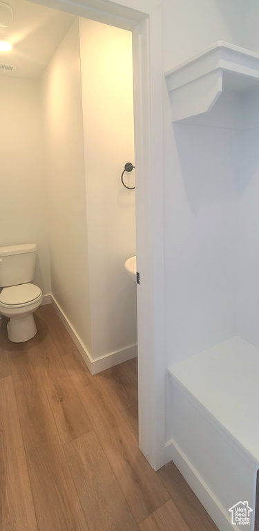 Bathroom featuring wood finished floors, toilet, and baseboards